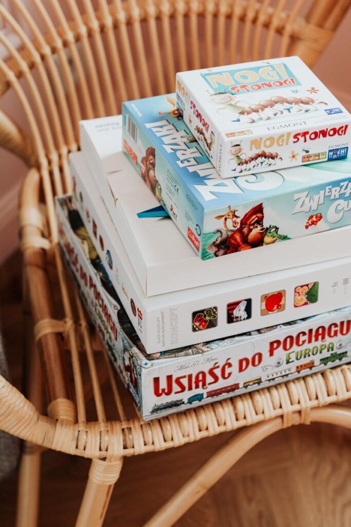 Close-up of various board games stacked on a woven rattan chair indoors. jogos de tabuleiro