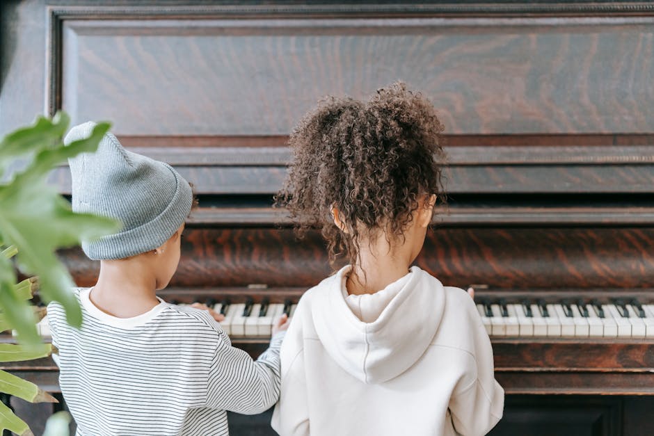 A boy and a girl practicing piano together indoors, fostering friendship and musical talent. crianças tocando piano. melhorar o qi em crianças