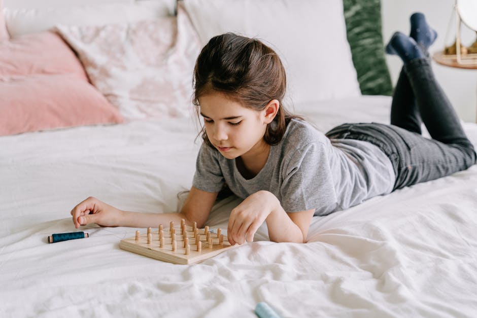 A young girl lying on a bed is absorbed in a mindful geoboard activity indoors. criança com um jogo de tabuleiro - melhorar qi em crianças