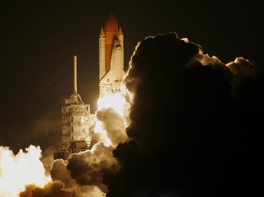 Dramatic capture of a space shuttle launching into the night sky, shrouded in smoke. NASA